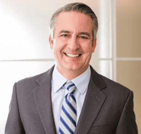 A man in suit and tie smiling for the camera.