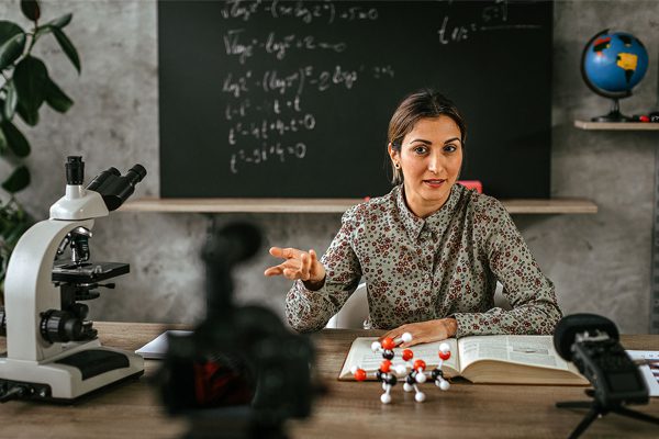 A woman sitting at a table with some sort of molecule model.