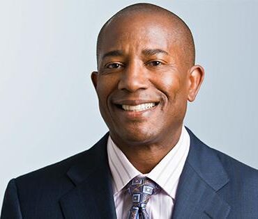 A man in a suit and tie smiling for the camera.