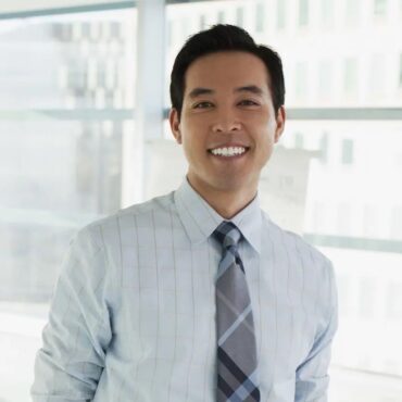 A man in a dress shirt and tie smiling.